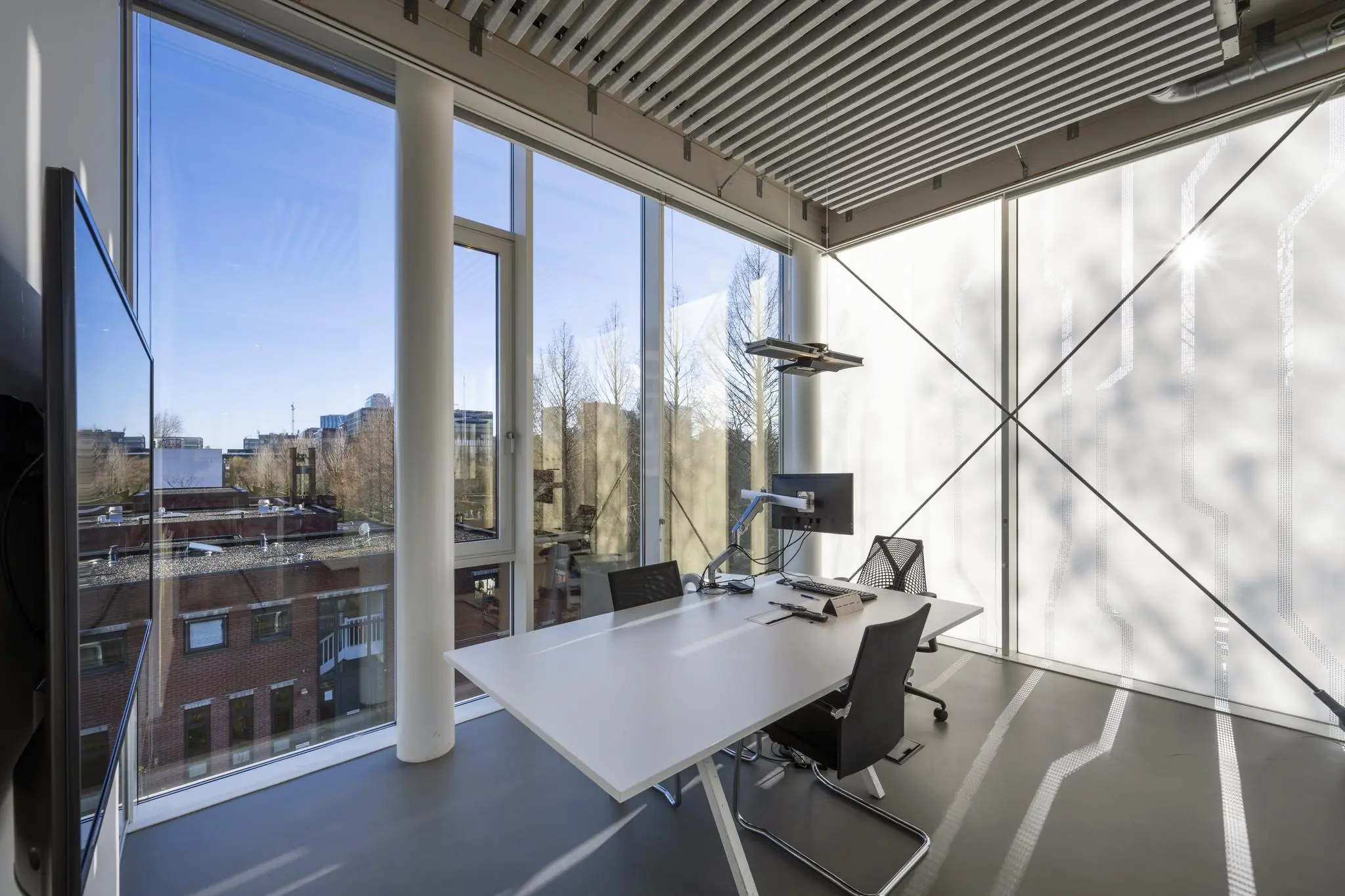 Modern kantoor met grote ramen aan de Fred. Roeskestraat, ingericht met strak bureau, bureaustoelen en computerscherm.
